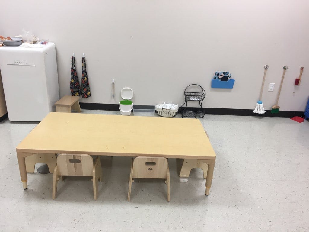 Children's table and chairs in a room with a refrigerator and cleaning supplies