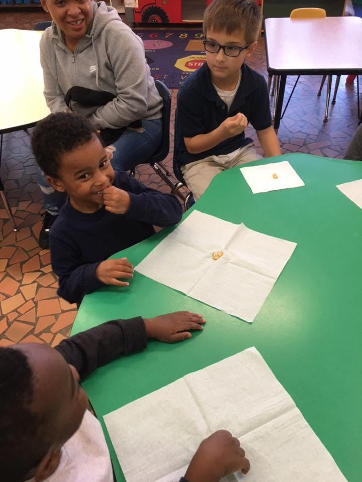 Adult and three children sitting at a green table with napkins