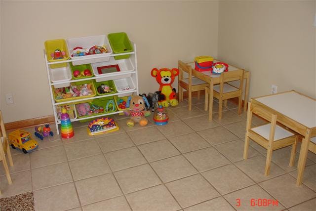 Playroom with toy shelf, stuffed animals, and small tables with chairs