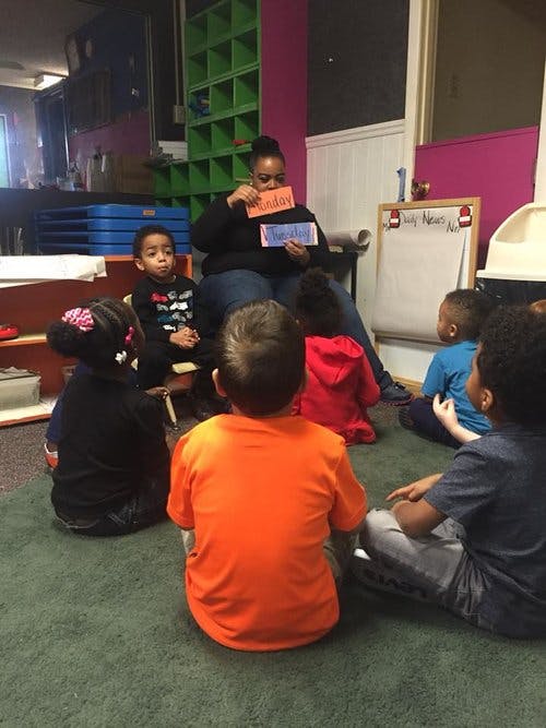 Person holding up cards to a group of children sitting on the floor