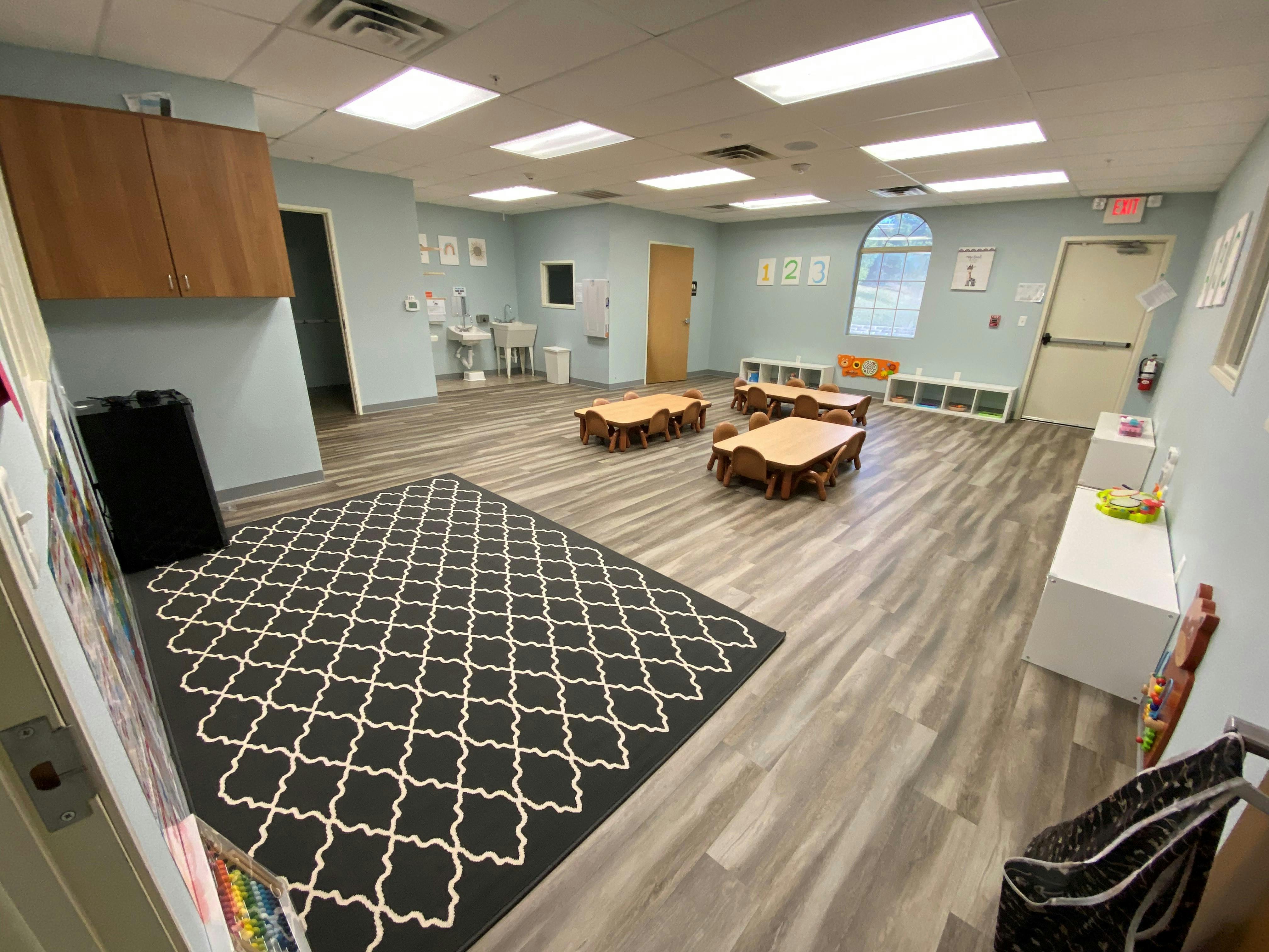Empty classroom with small tables and a patterned rug