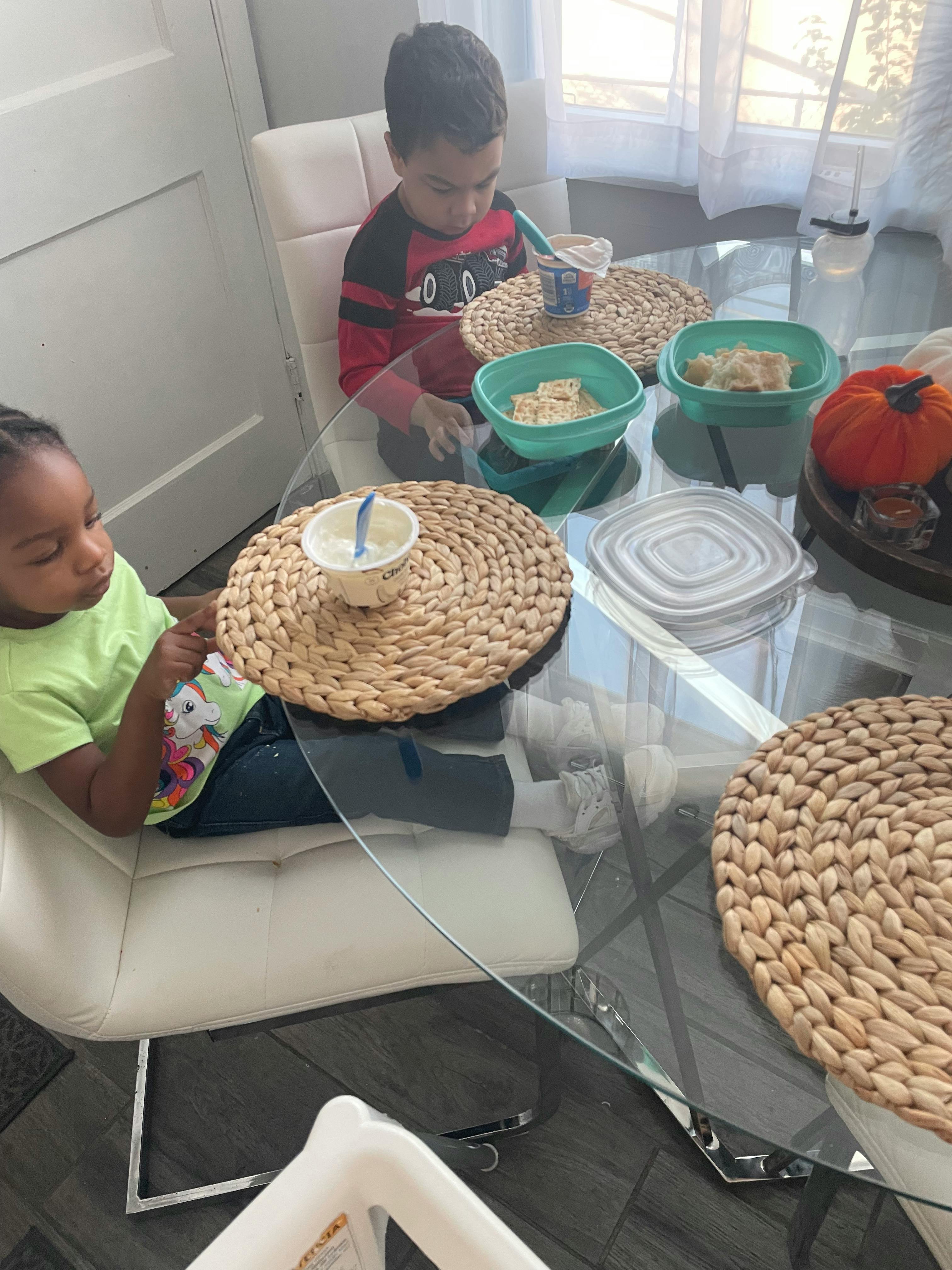 Two children sitting at a table with food