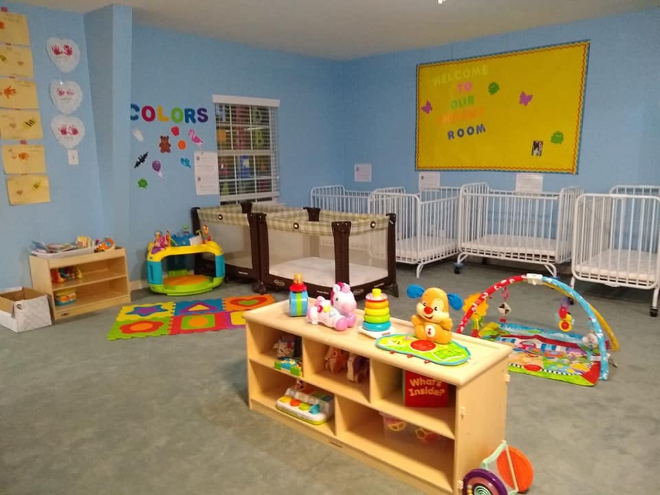 Nursery room with multiple cribs and infant play items
