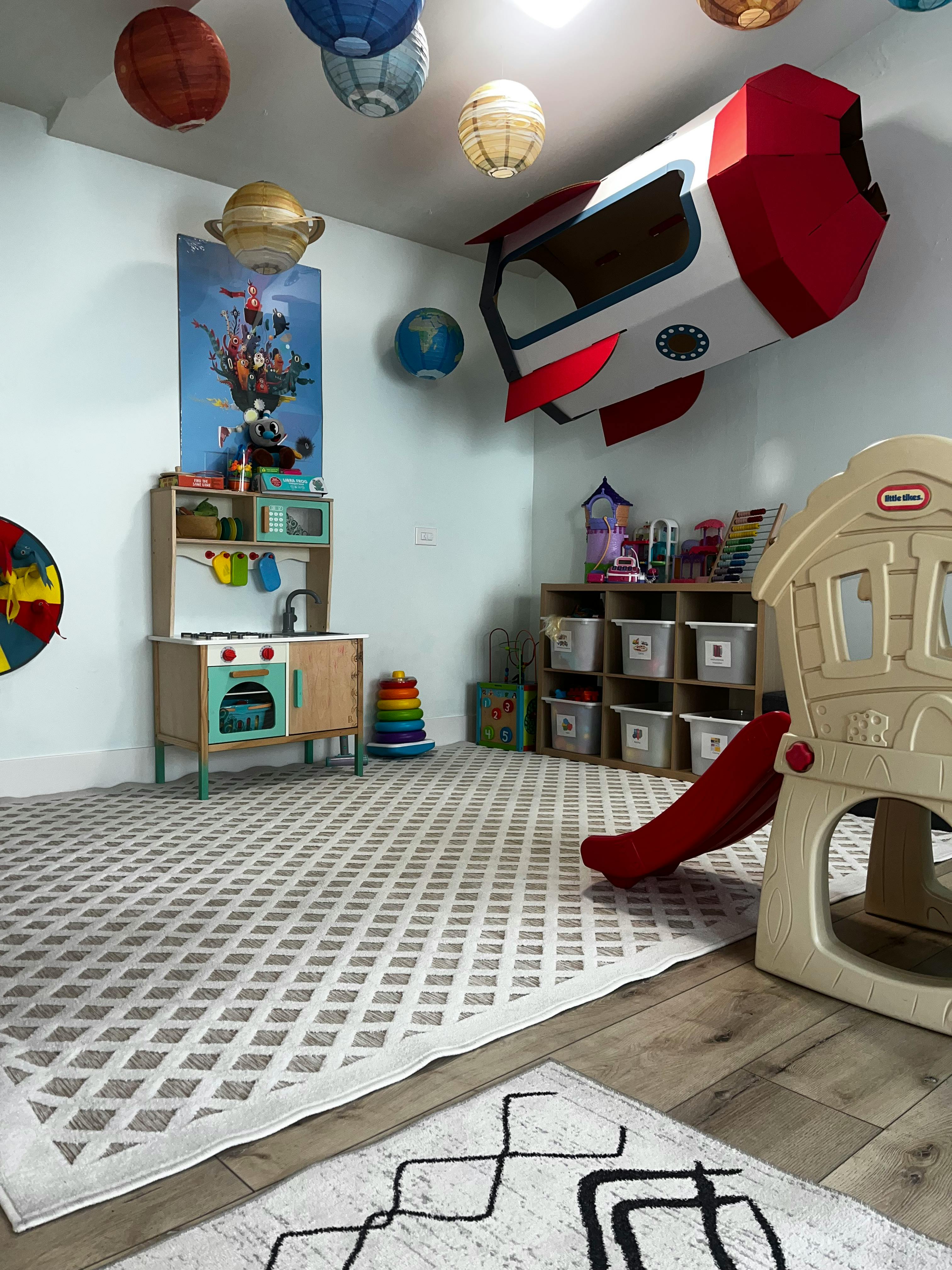 Playroom with toy kitchen, slide, and rocket decoration