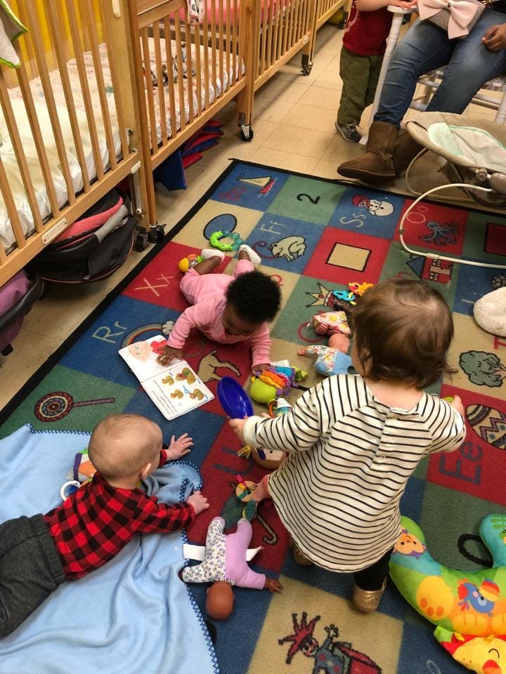 Three children playing with toys on a colorful rug