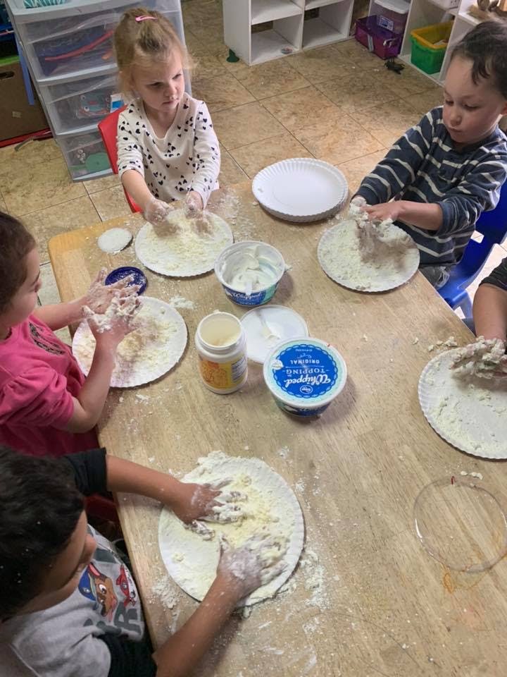 Children playing with dough on paper plates at a table