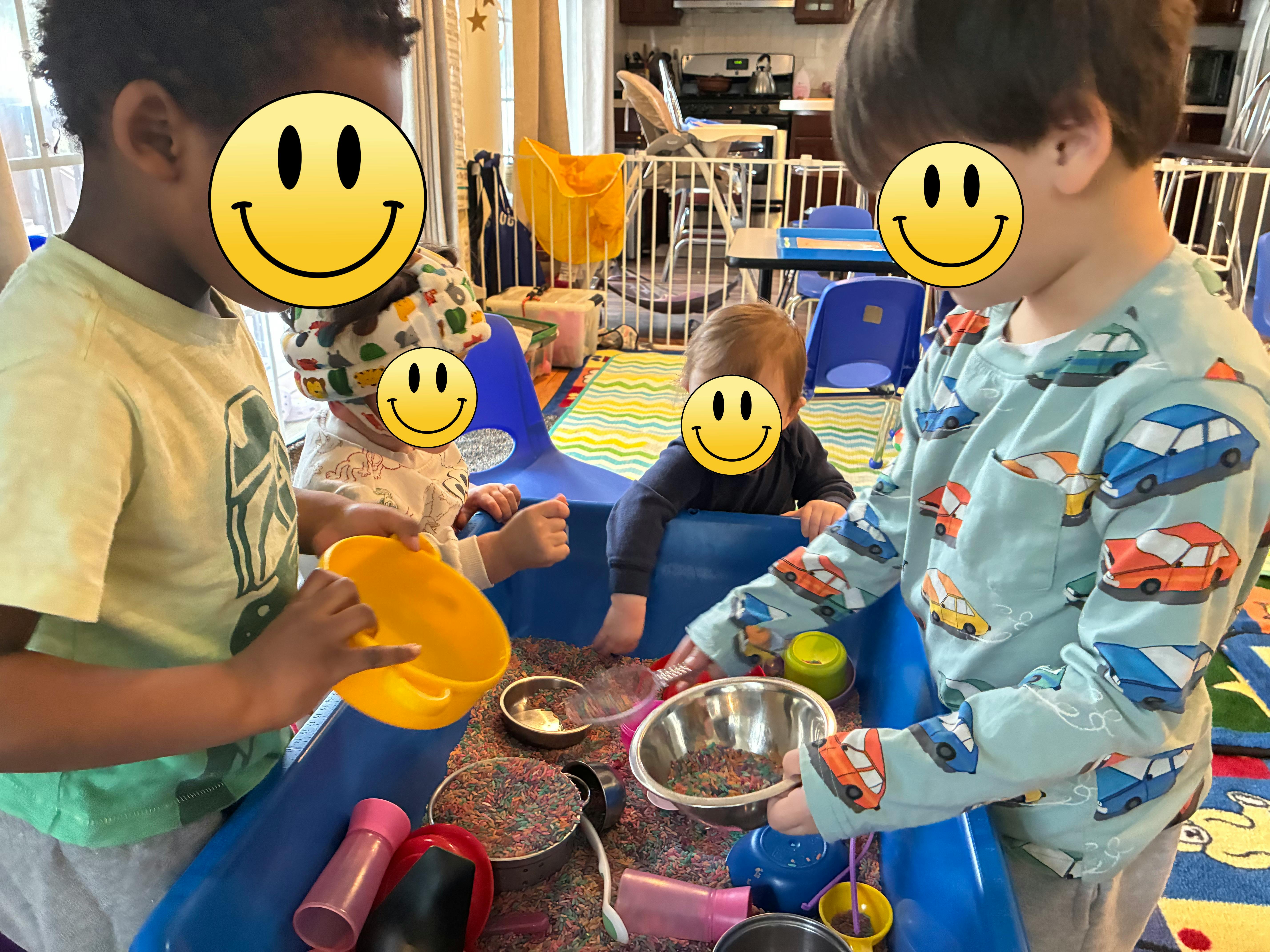 Group of children playing with rice and containers in a sensory bin