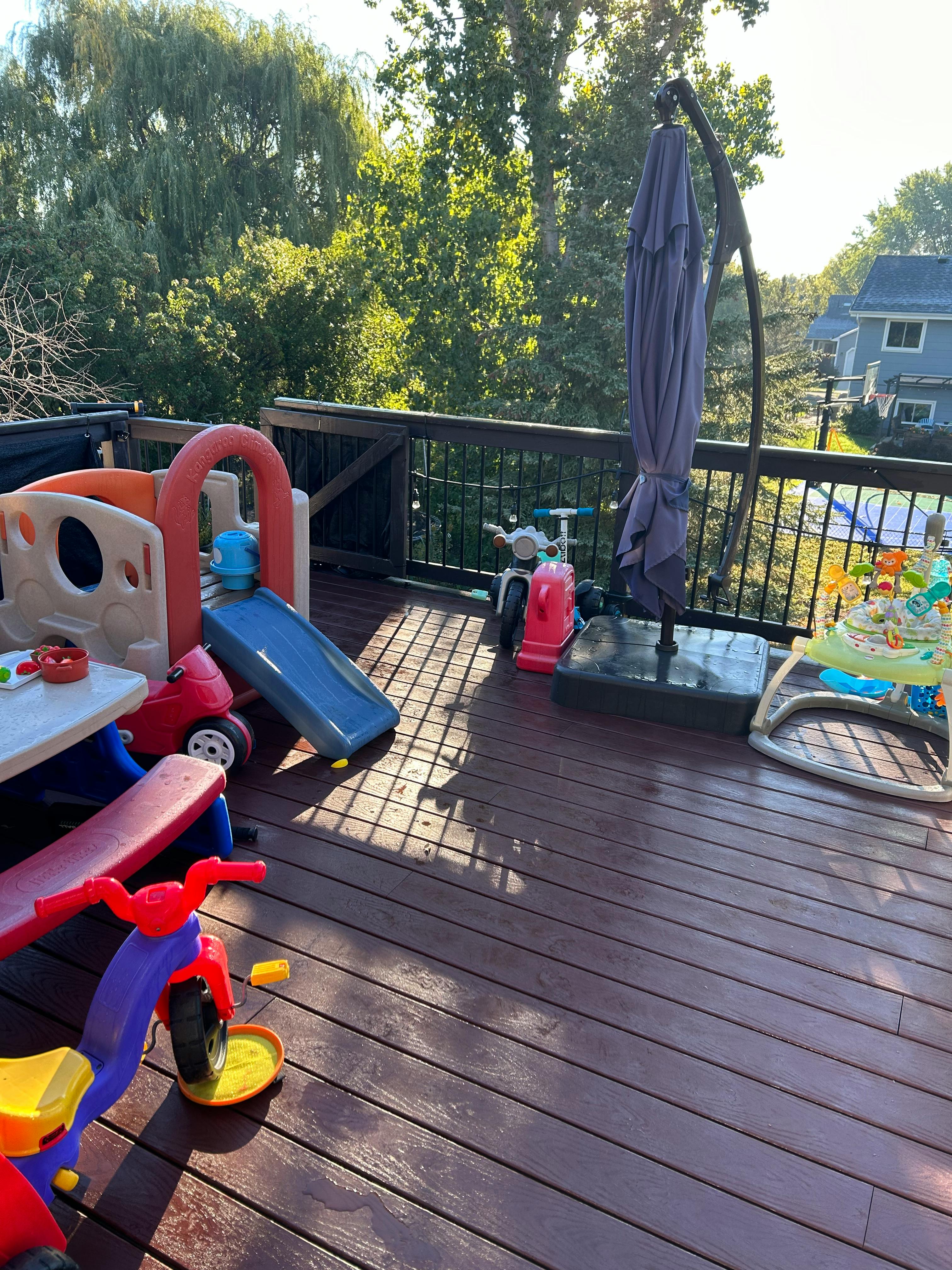Outdoor deck with children's play equipment and a closed umbrella