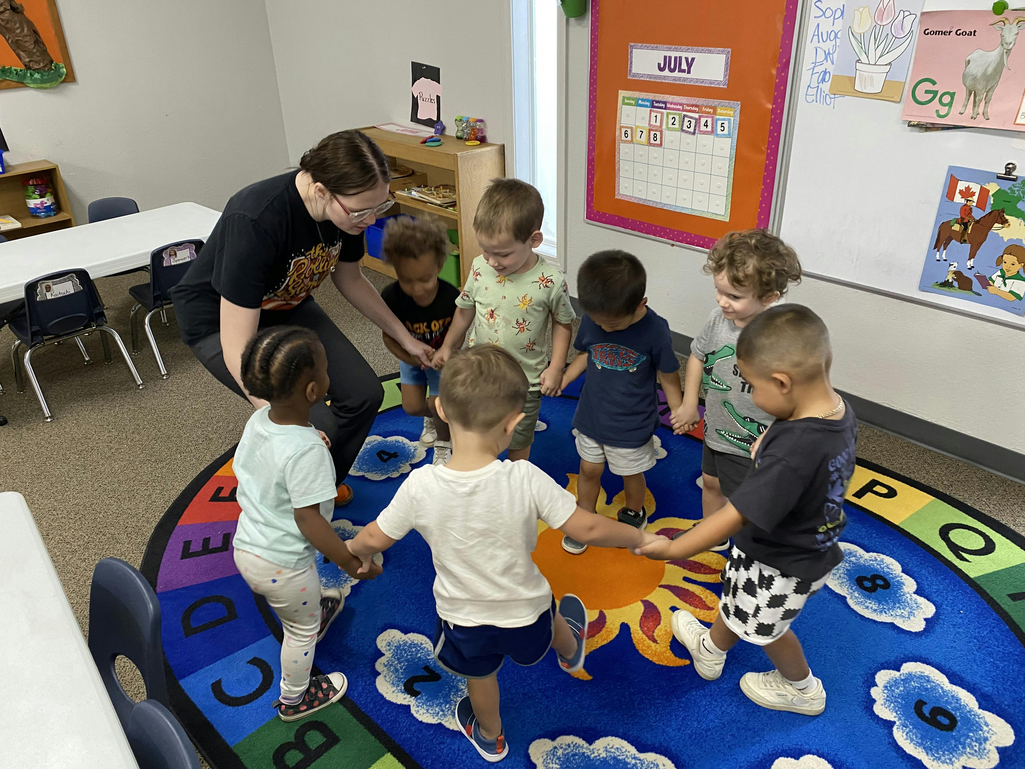 Adult and children holding hands in a circle on a rug