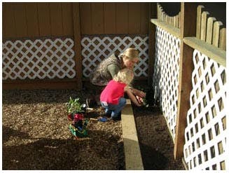 Adult and child planting in a garden