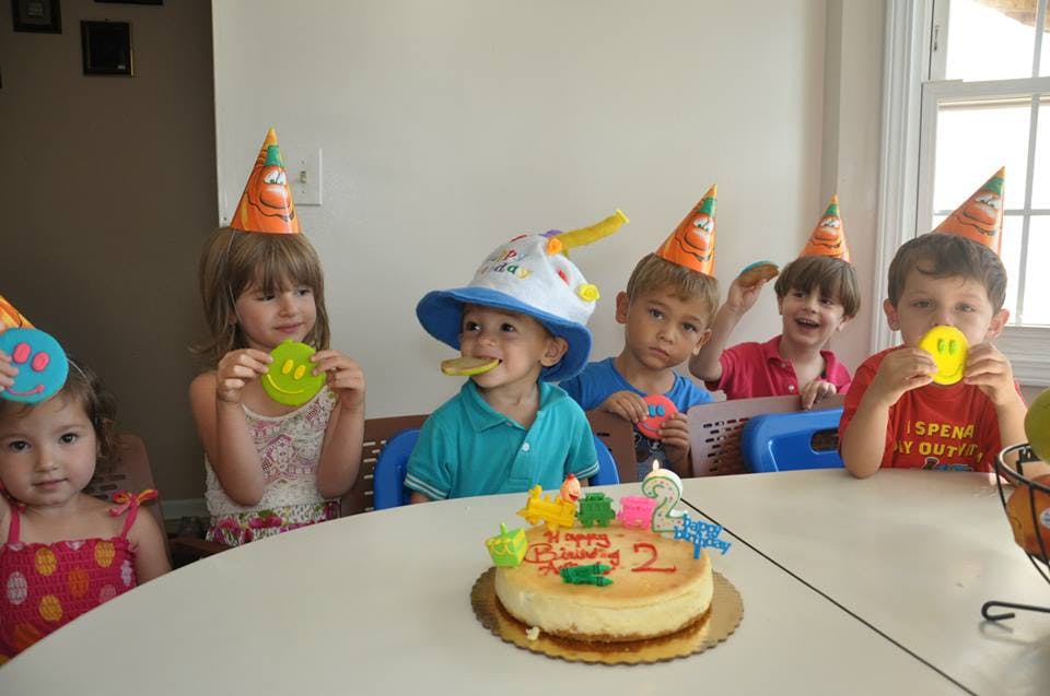 Children in party hats sitting at a table with a birthday cake