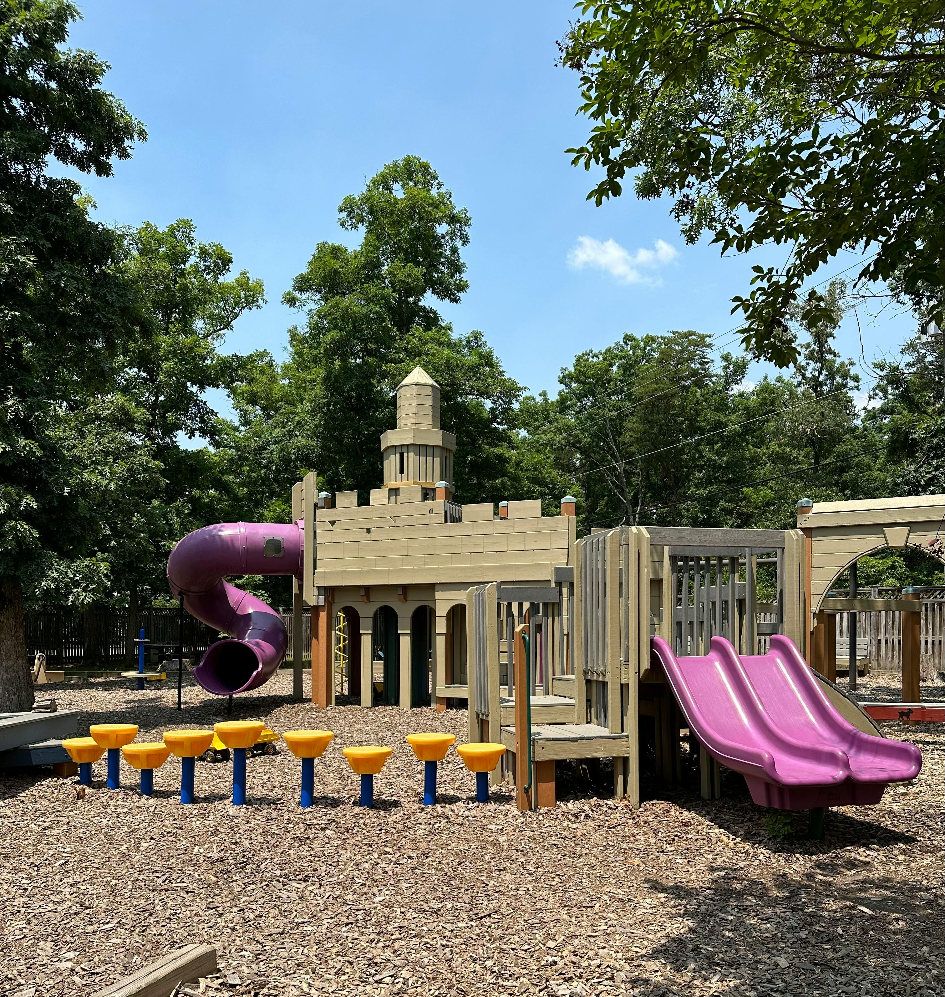 Playground with castle-like structure, purple slides, and yellow stepping pods
