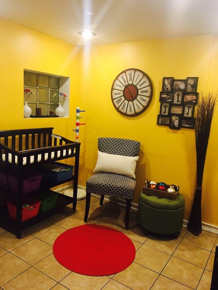 Nursery room with a crib, patterned chair, and large wall clock