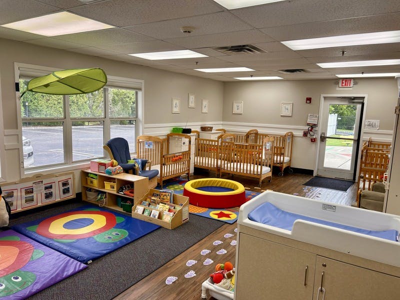 A room with several cribs, a changing table, and play mats for children