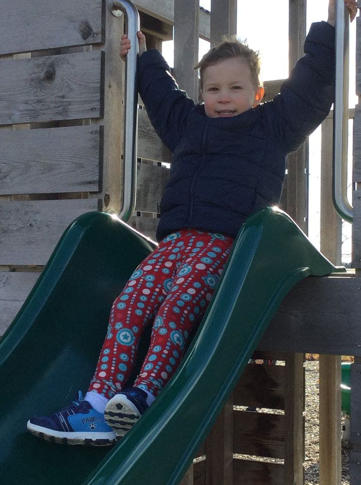 Child sitting at the top of a playground slide