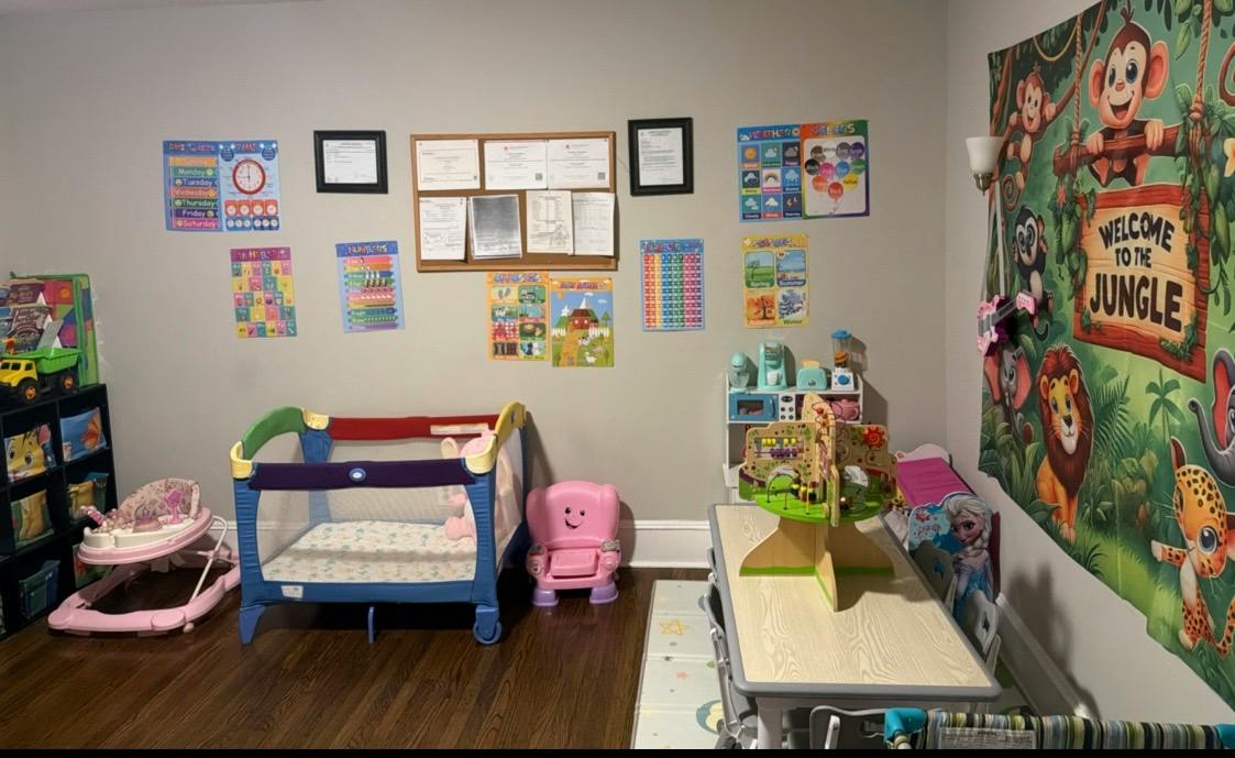 Childcare room with a playpen, children's table, chairs, and educational posters