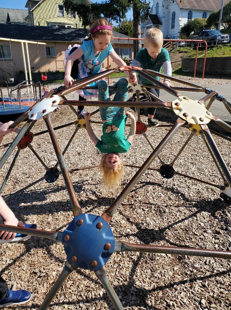 Children playing on a geodesic dome climber at a playground