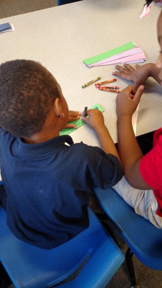 Two children drawing with crayons at a table