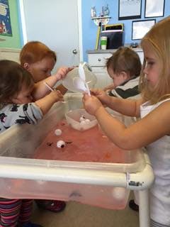 Children playing with water and toys in a sensory bin
