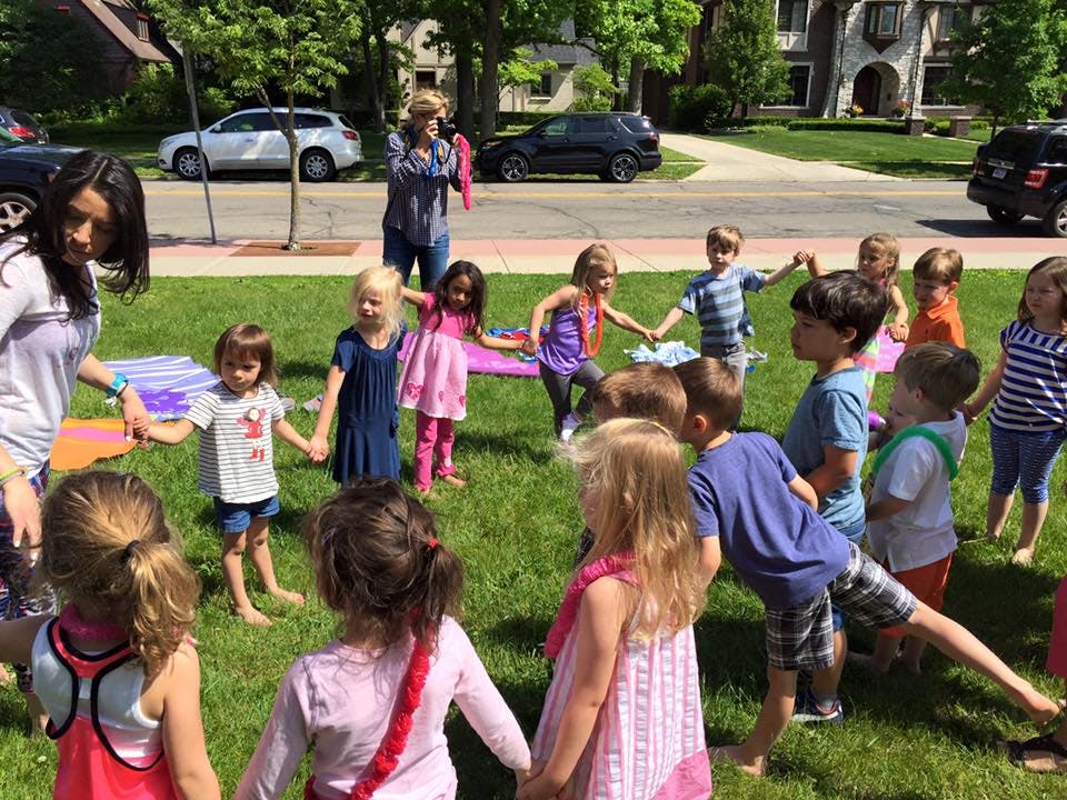 Adults and children holding hands in a circle on grass