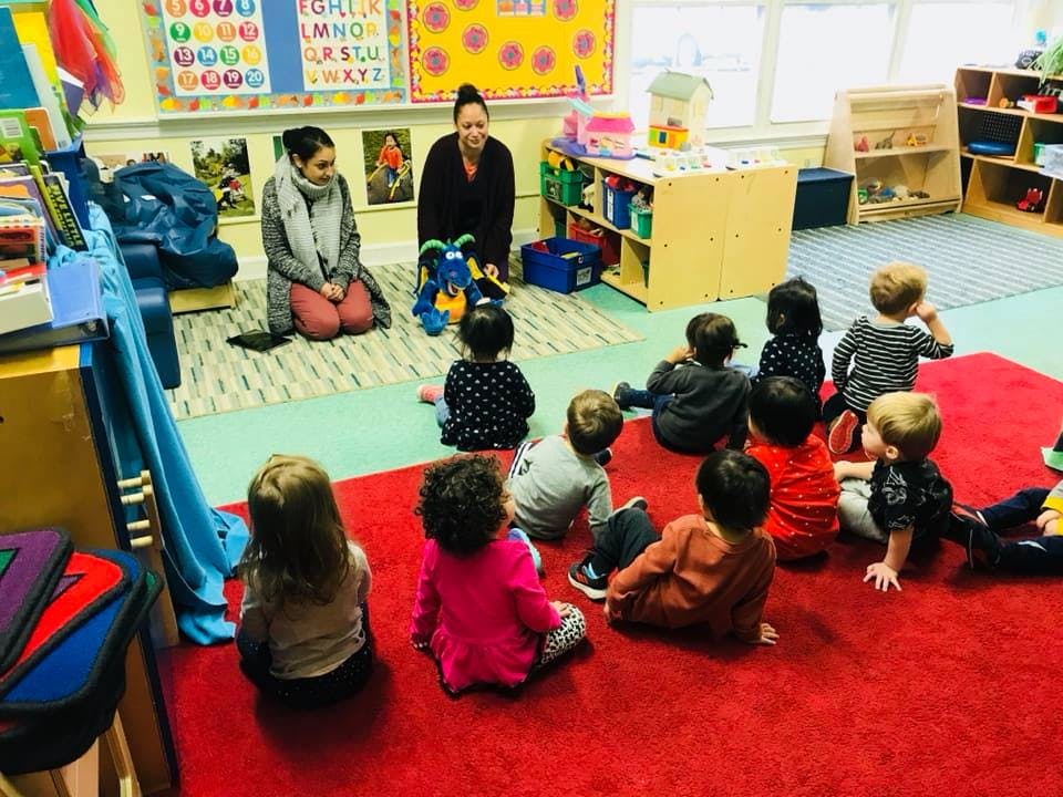 Two people with a group of children in a classroom