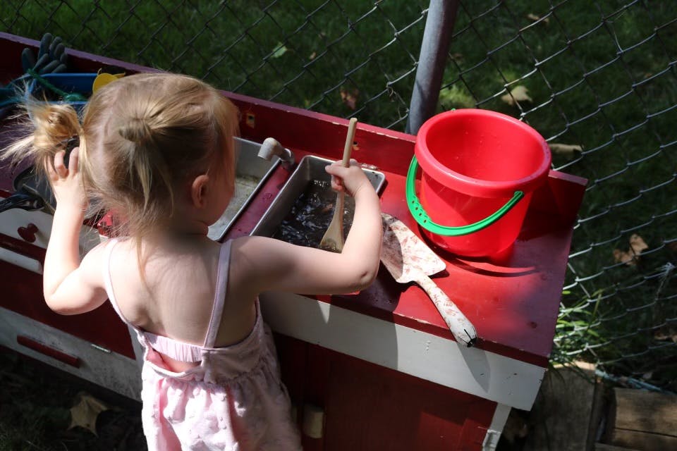 Child playing with mud in a play kitchen