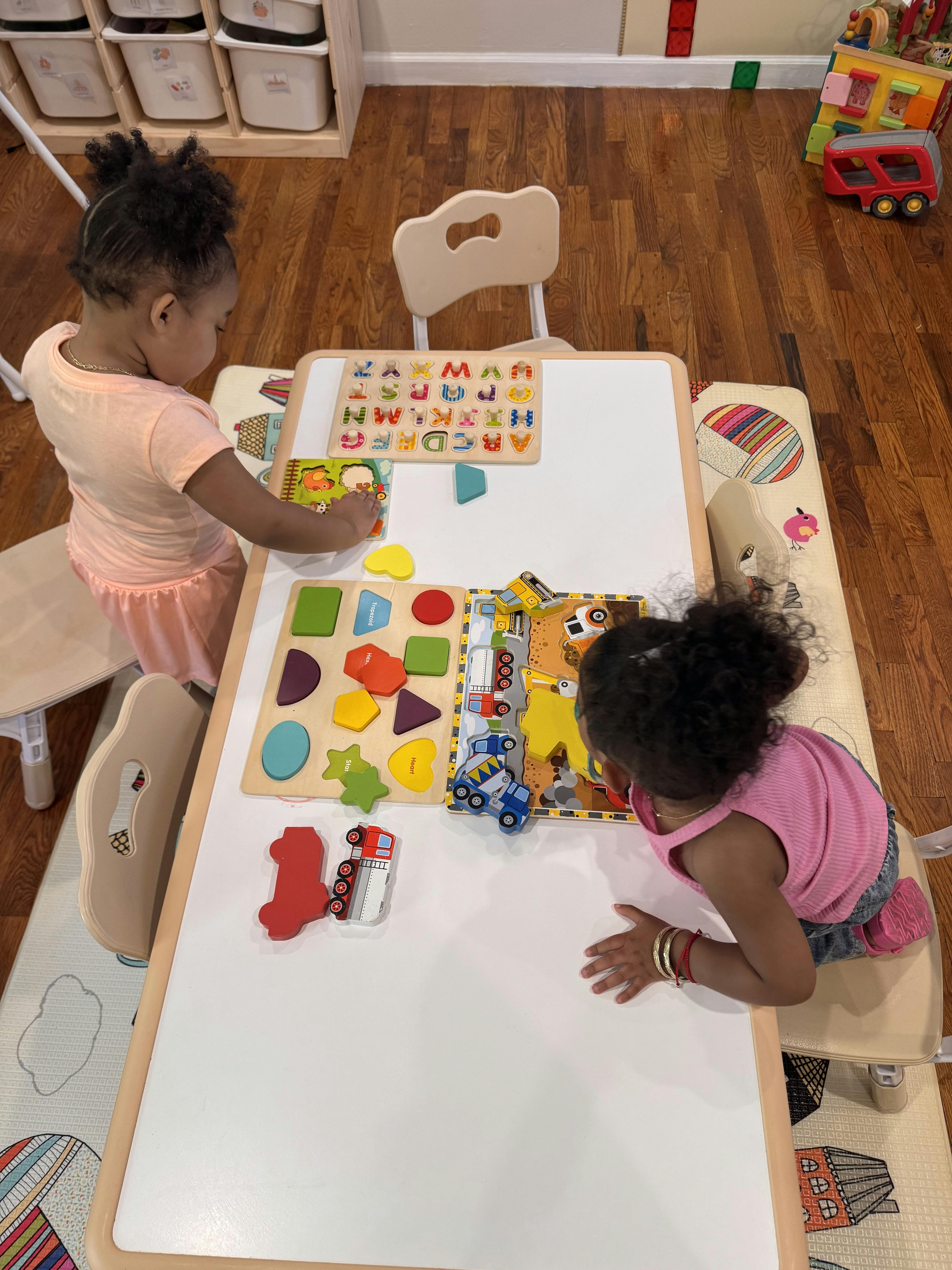 Two children playing with wooden puzzles at a table