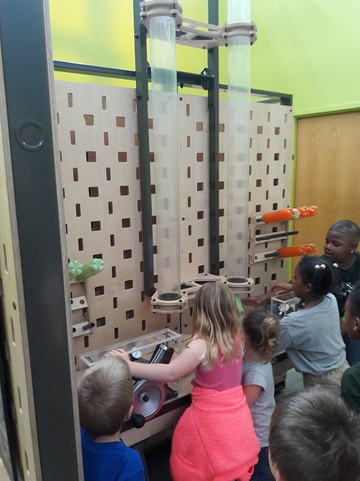 Children playing with an interactive wall display with tubes and levers