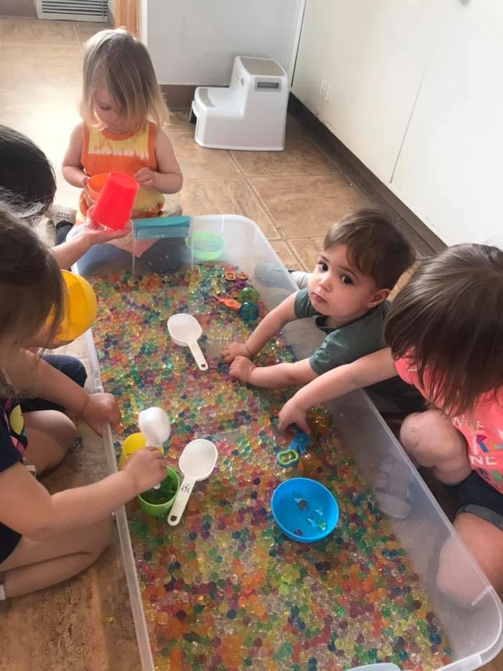 Children playing with water beads in a large clear bin