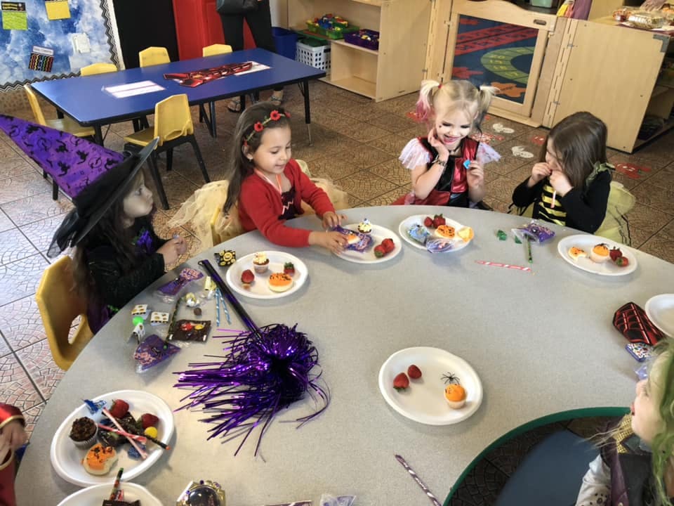 Children in costumes sitting around a table with plates of food
