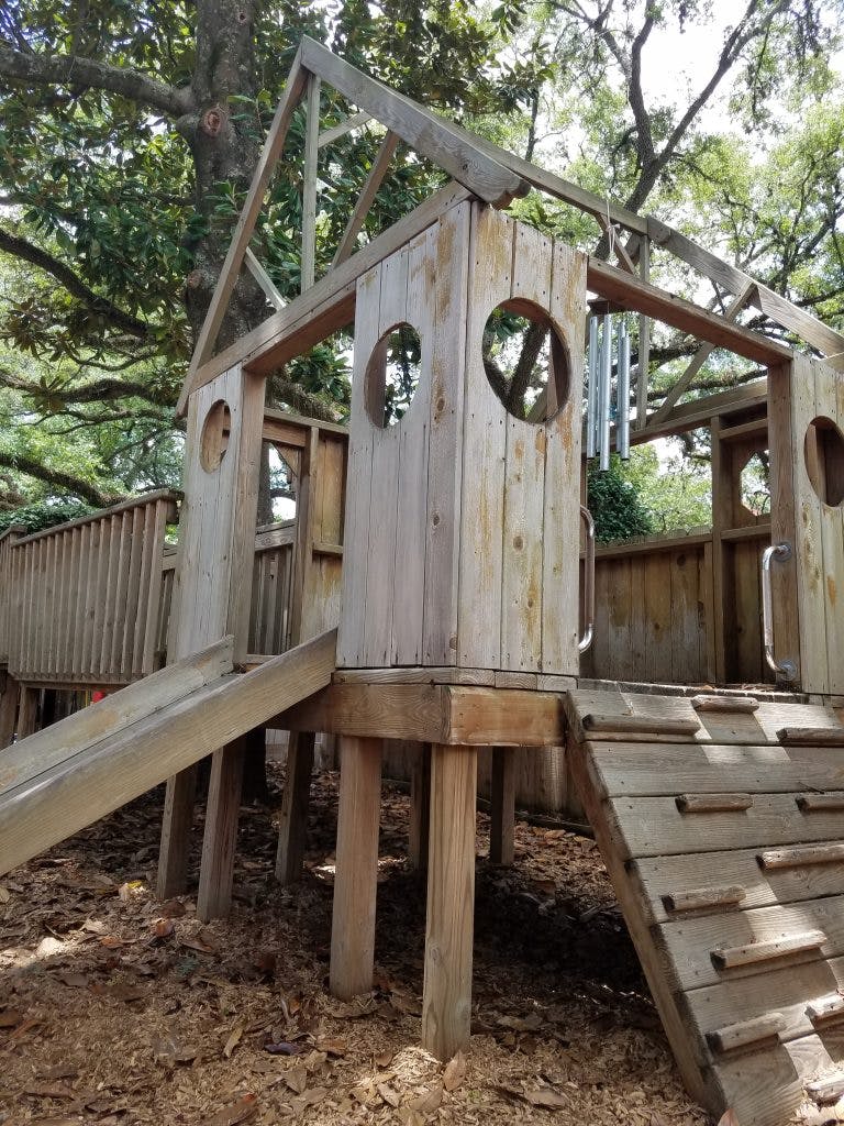 Wooden playhouse with slide and climbing ramp