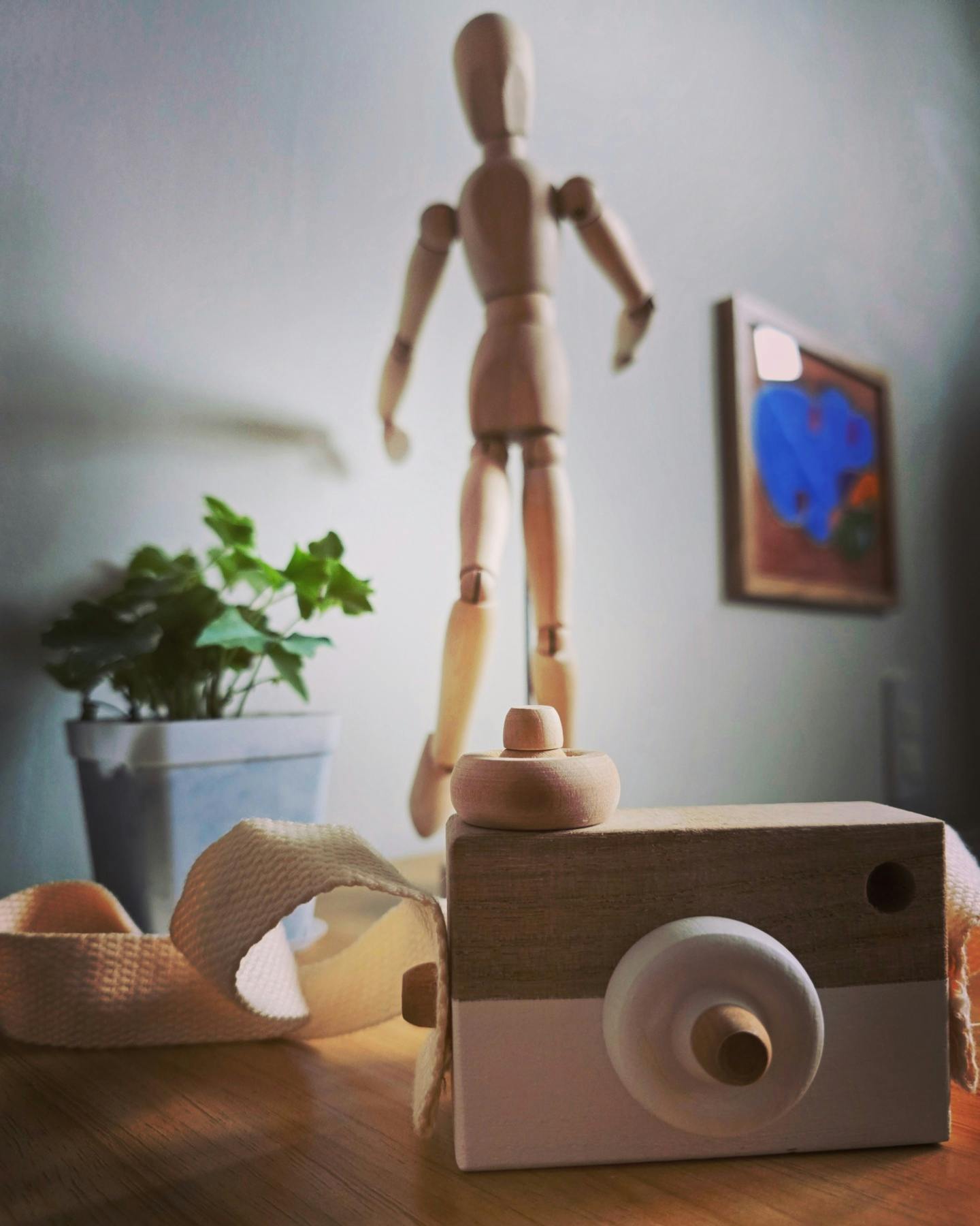Wooden art mannequin standing on a wooden toy camera