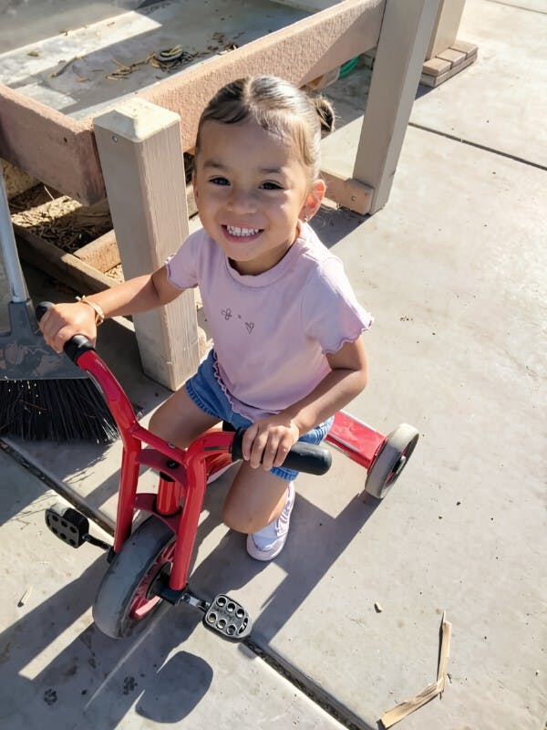 Child riding a red tricycle outdoors