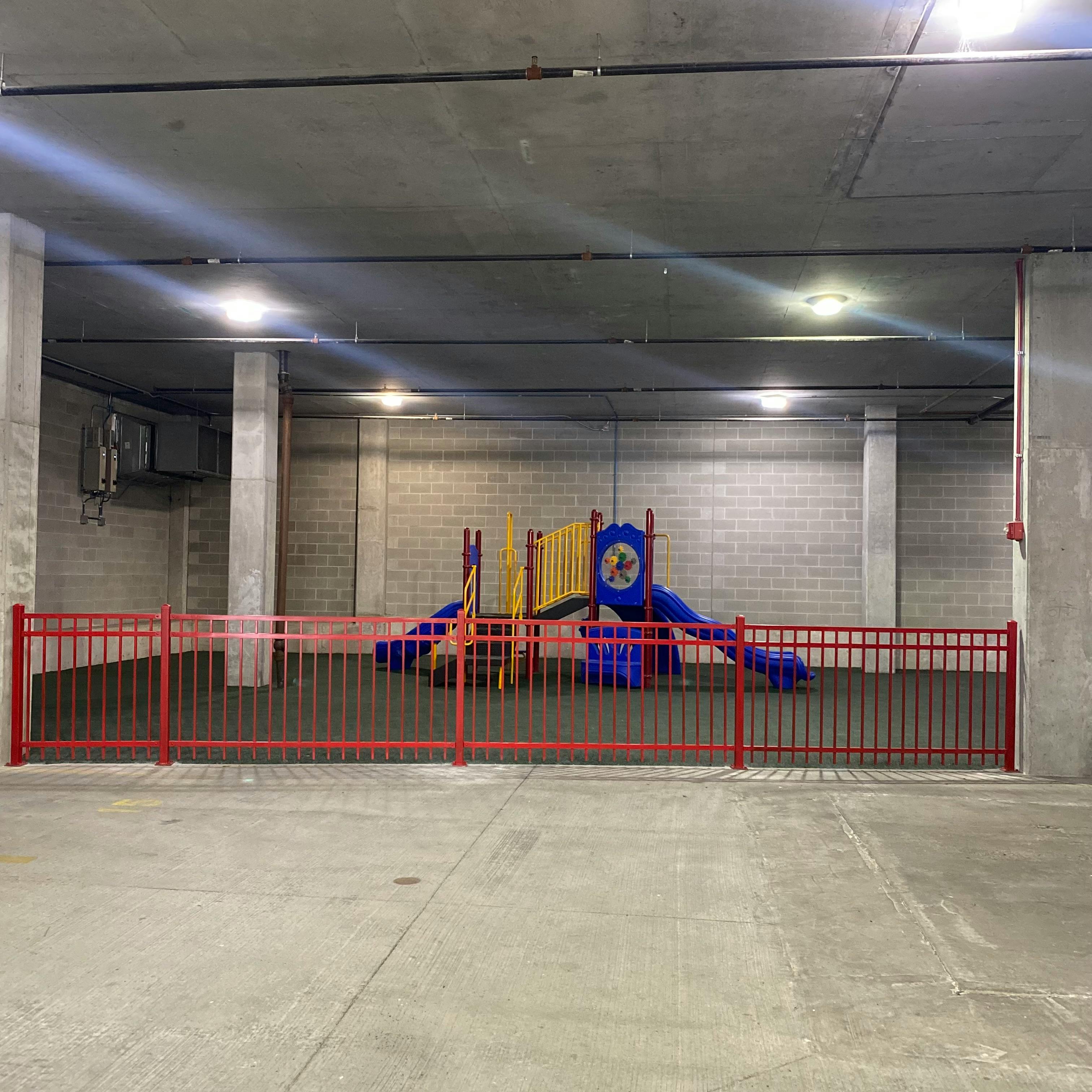 Playground structure behind a red fence in an indoor area