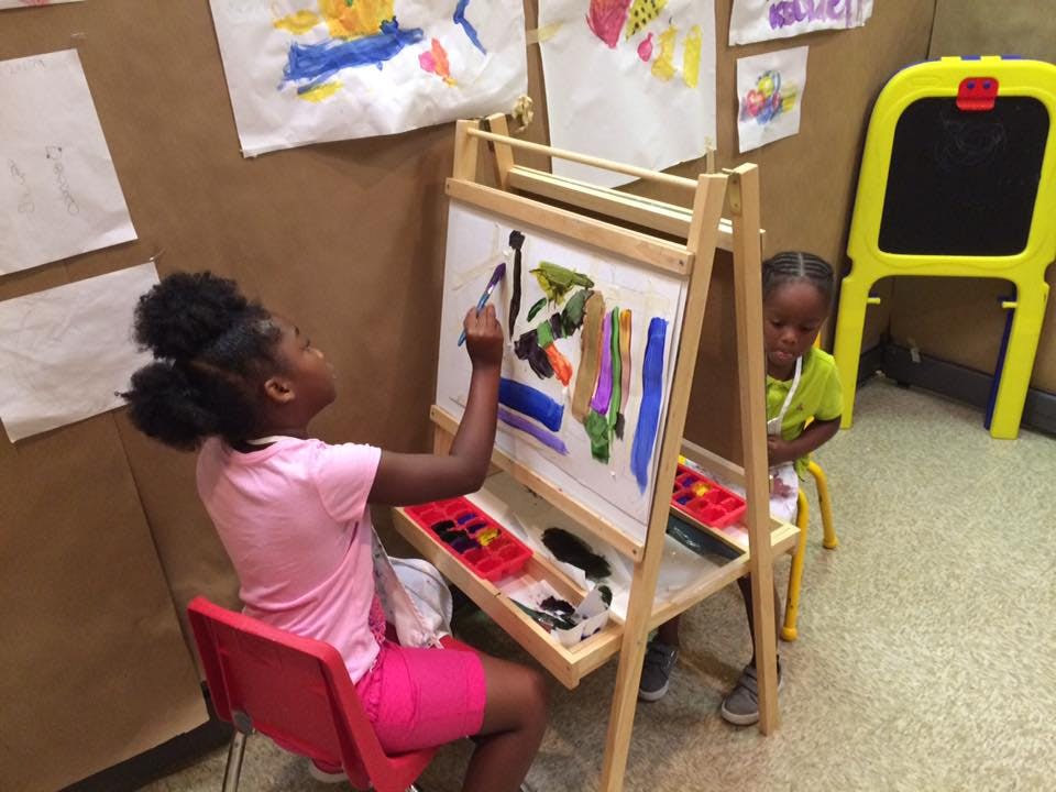 Child painting at an easel in a classroom