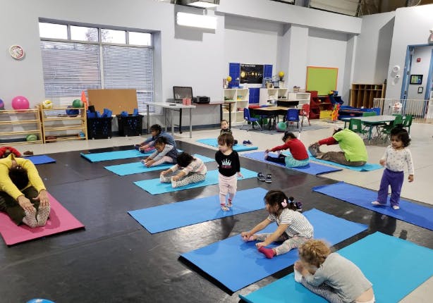 People and children stretching on yoga mats in a room