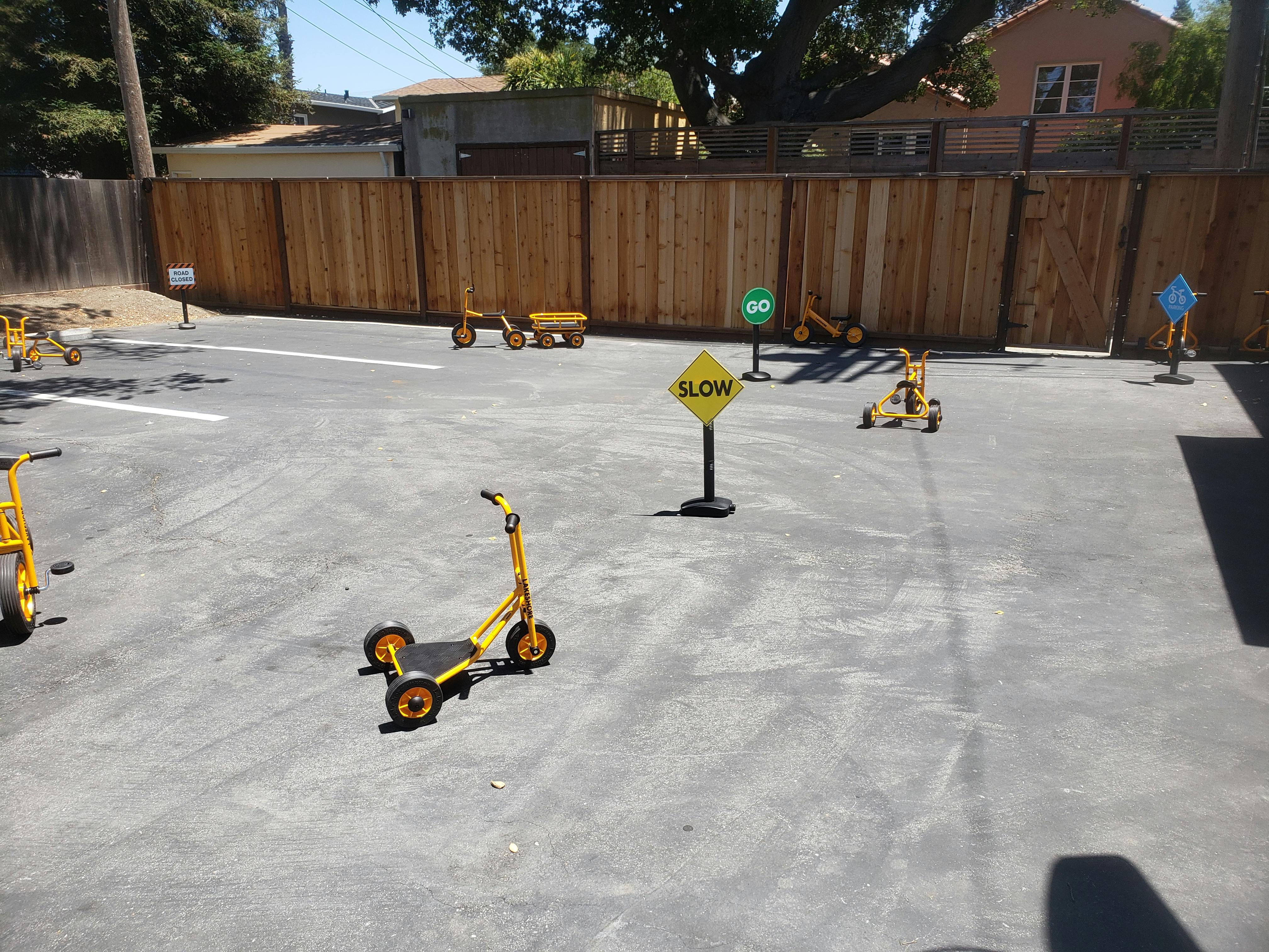 Playground with yellow scooters and a "SLOW" sign