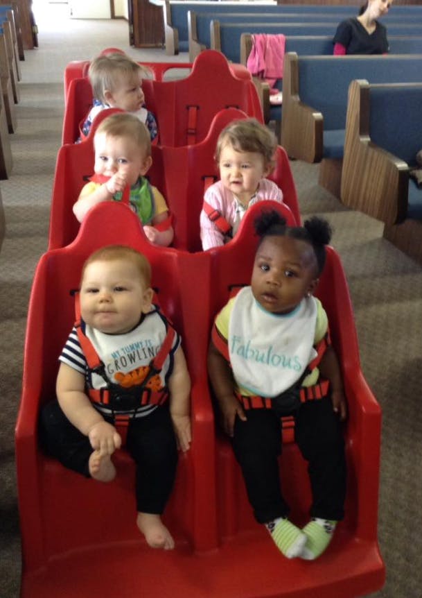 Multiple babies sitting in red seats