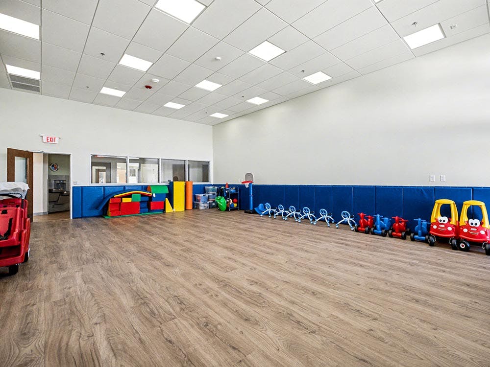 Playroom with ride-on toys, climbing blocks, and an exit sign