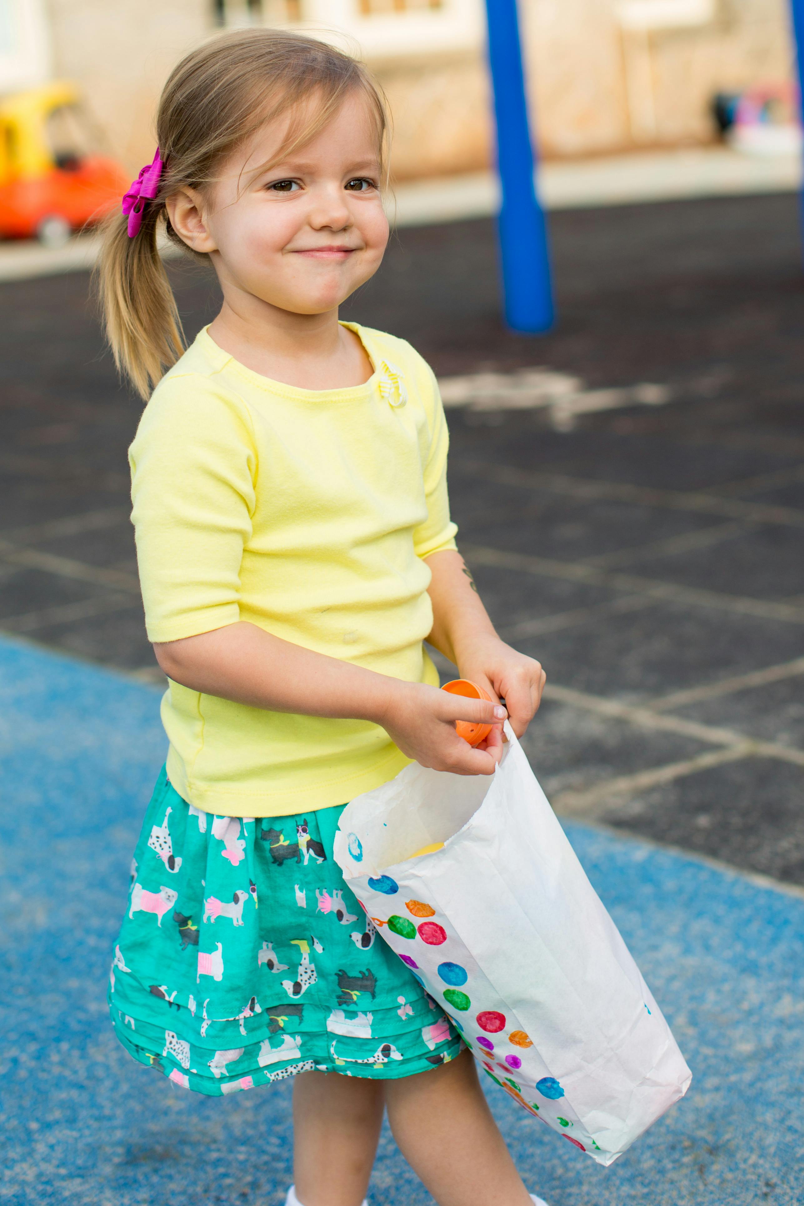 Child holding a white bag with colorful dots and an orange object