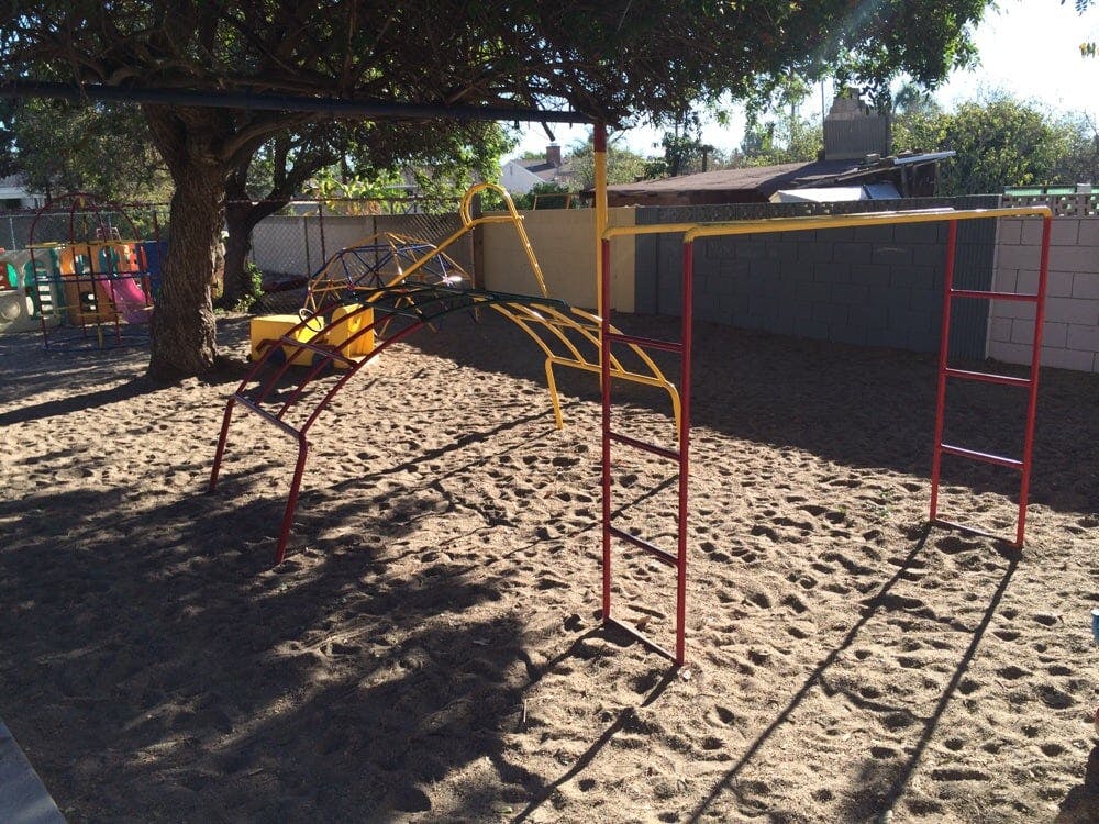 Playground with monkey bars and a swing set over sand