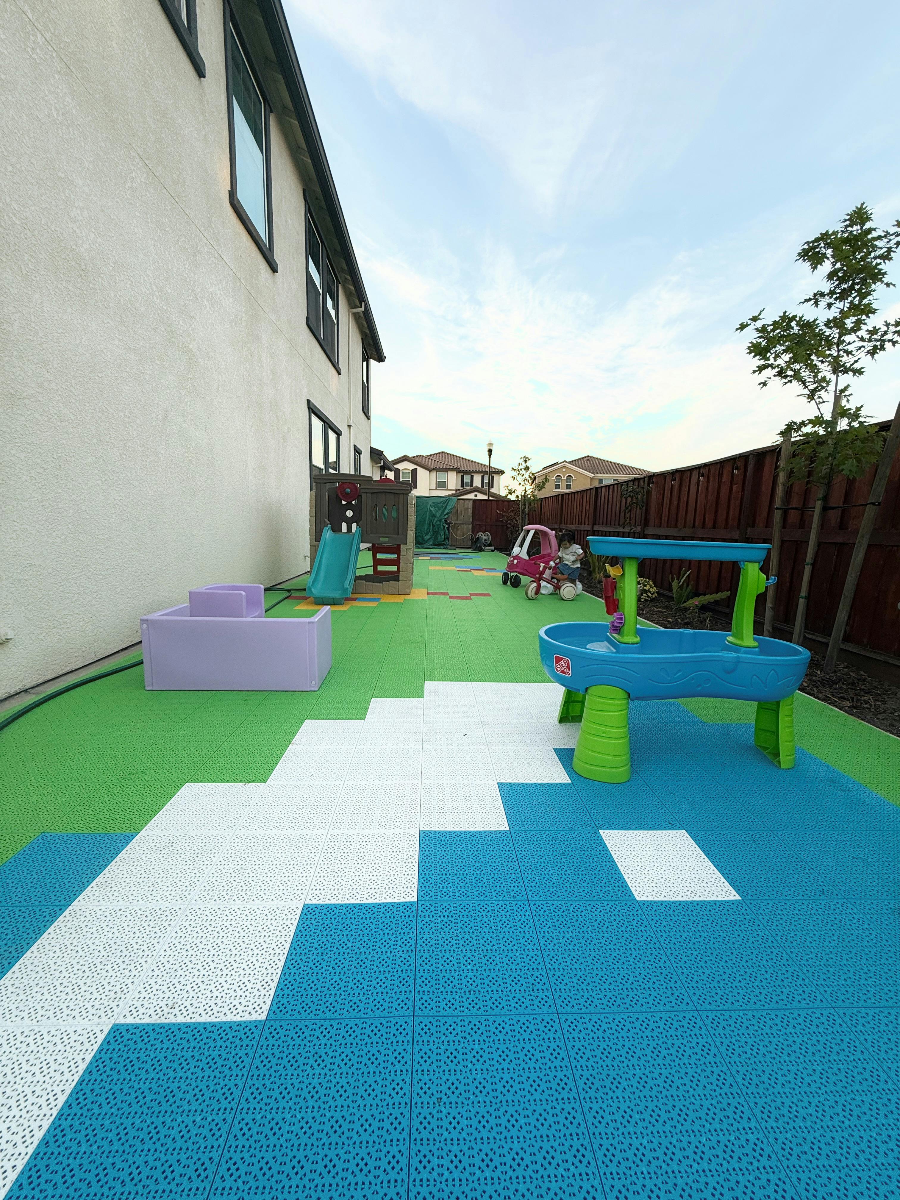 Child on a toy car in a backyard with playground equipment