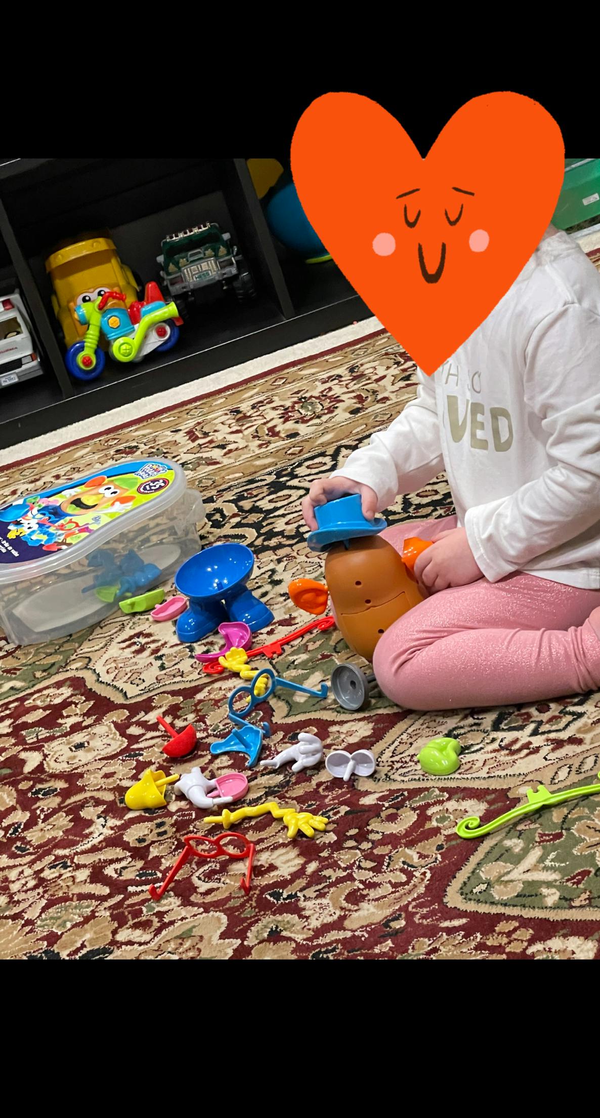 Child playing with a potato toy and plastic accessories on a patterned rug