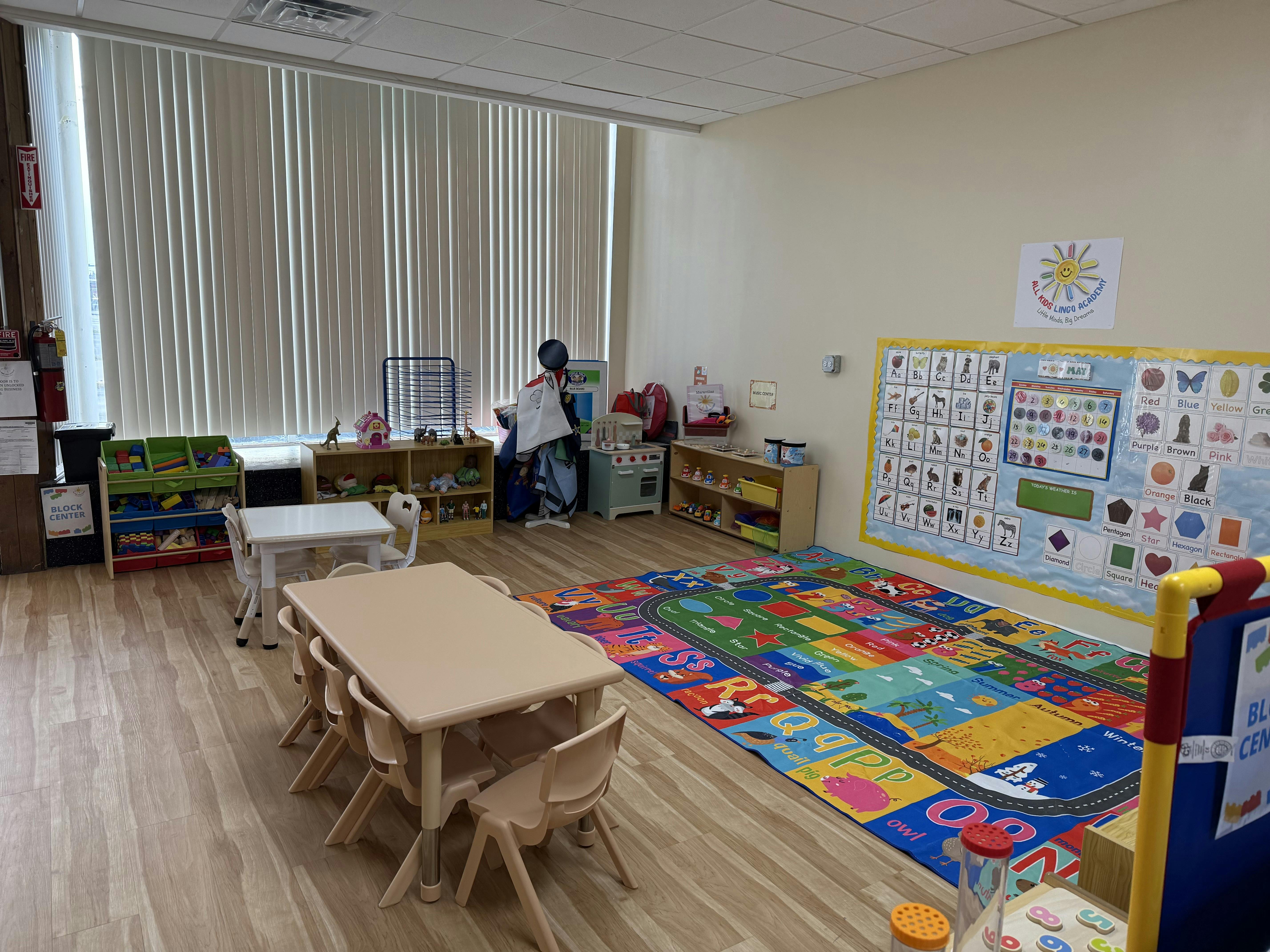 Child standing at a table in a classroom with a colorful rug