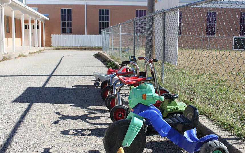 Row of tricycles parked along a fence