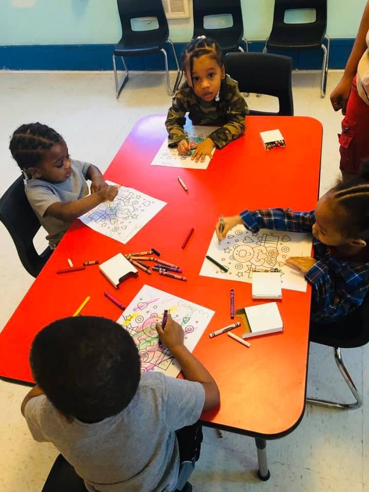 Children coloring at a red table in a classroom