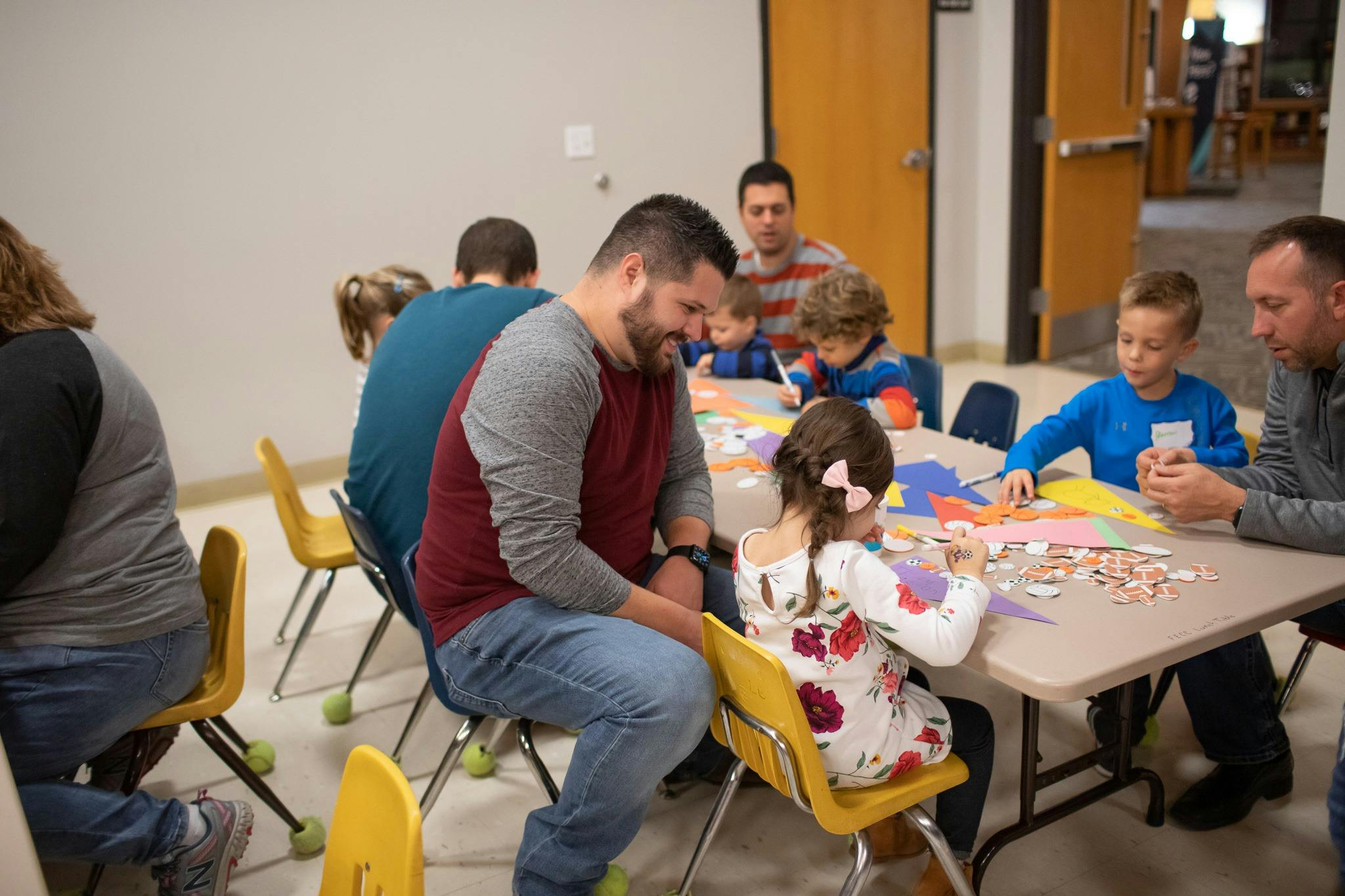Adults and children sitting at tables doing crafts