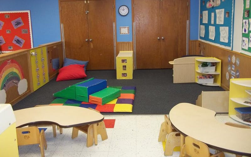Children's classroom with small tables, floor cushions, and colorful foam play blocks
