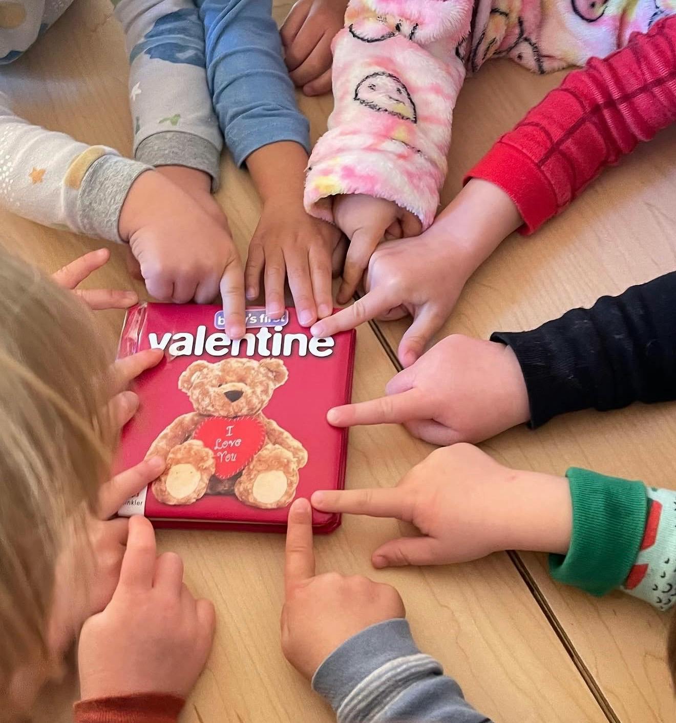 Group of children pointing at a book titled Valentine