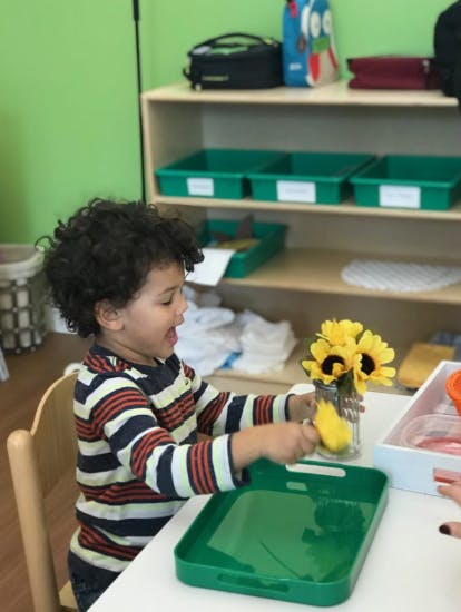 Child playing with a yellow object at a table